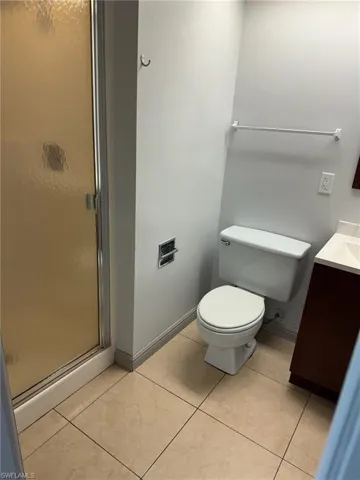 Bathroom featuring an enclosed shower, toilet, vanity, and tile patterned floors