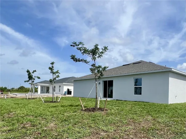 Rear view of house with stucco siding and a lawn