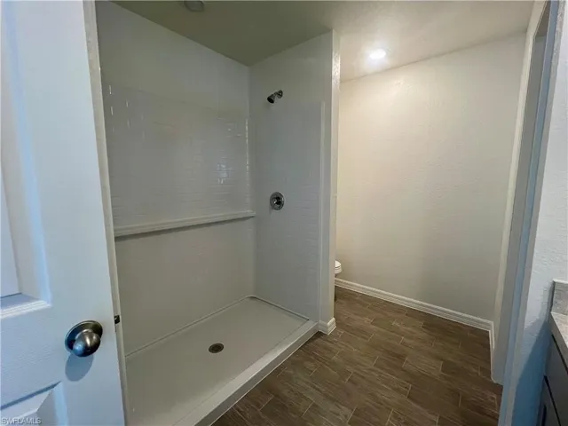 Full bathroom with vanity, wood finished floors, and a tile shower