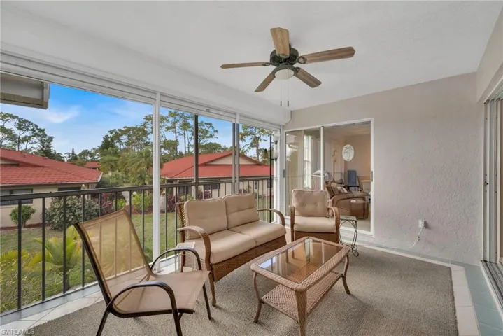 Sunroom featuring a textured wall, a ceiling fan, tile patterned flooring, and an outdoor lounge area