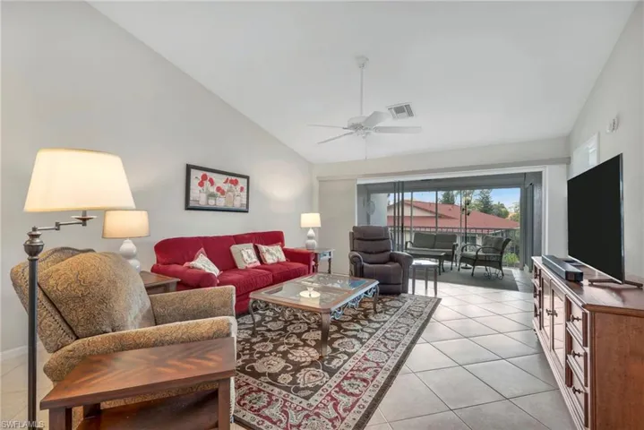 Living area featuring vaulted ceiling, a ceiling fan, and light tile patterned floors