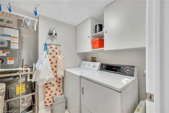Laundry area featuring cabinet space, independent washer and dryer, and water heater & AC