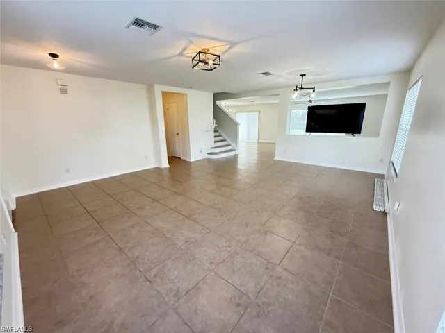 Unfurnished living room with tile patterned floors, stairway, and plenty of natural light