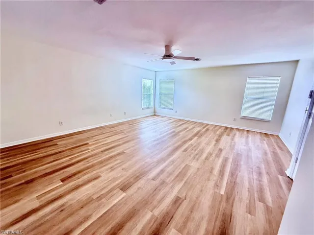 Unfurnished room with light wood-style flooring, a ceiling fan, and baseboards