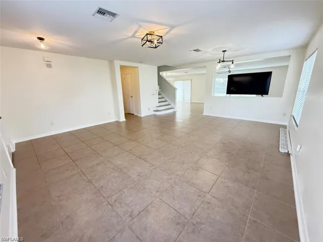 Unfurnished living room with tile patterned floors, stairway, and baseboards