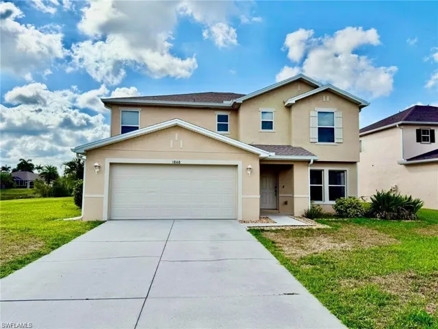 Traditional-style house with stucco siding, a front lawn, concrete driveway, and a garage