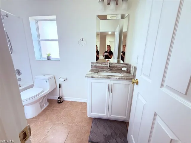 Bathroom featuring vanity, toilet, tile patterned flooring, baseboards, and  shower combination