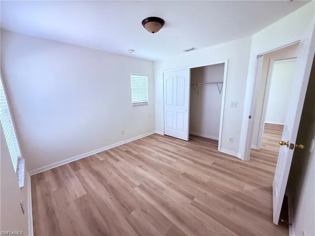 Unfurnished bedroom with light wood finished floors, a closet, and baseboards