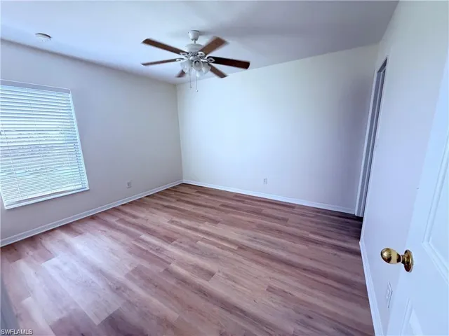 Spare room featuring a ceiling fan, wood finished floors, baseboards, and a smoke detector