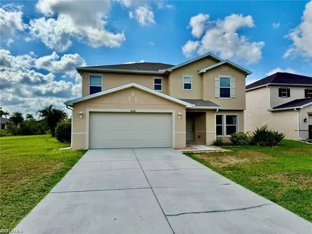 Traditional-style home featuring stucco siding, concrete driveway, a front lawn, and a garage