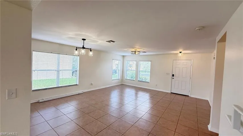 Spare room featuring tile patterned flooring, baseboards, and a baseboard radiator