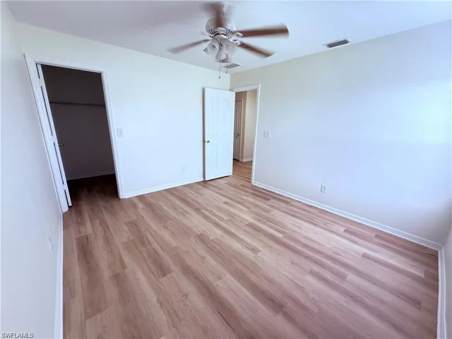 Unfurnished bedroom with light wood-type flooring, a spacious closet, baseboards, a closet, and ceiling fan