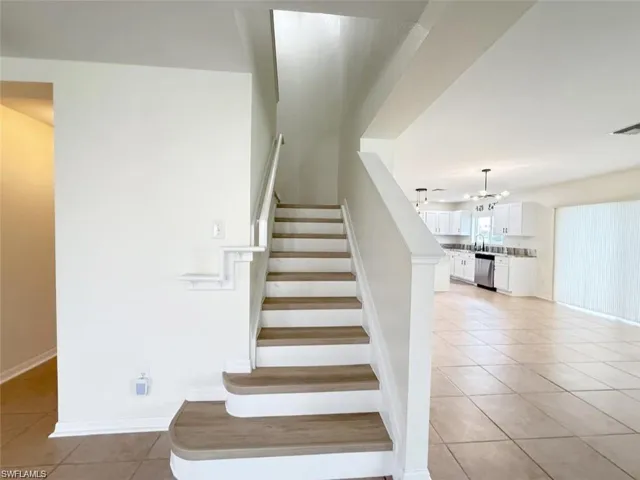 Stairs featuring tile patterned floors, a chandelier, and baseboards