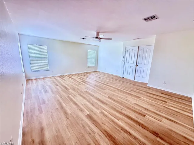 Spare room featuring a ceiling fan, light wood-type flooring, healthy amount of natural light, and baseboards