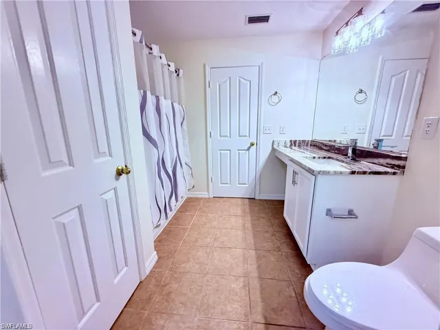 Full bathroom featuring vanity, toilet, tile patterned flooring, and curtained shower