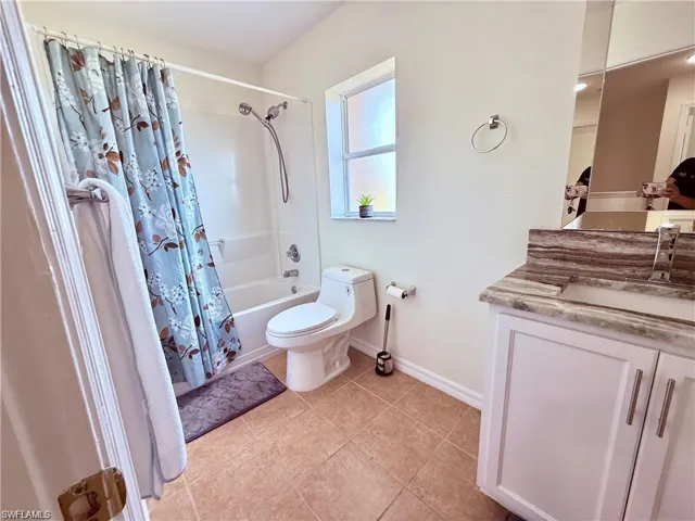 Full bathroom with vanity, toilet, shower / tub combo, baseboards, and tile patterned floors