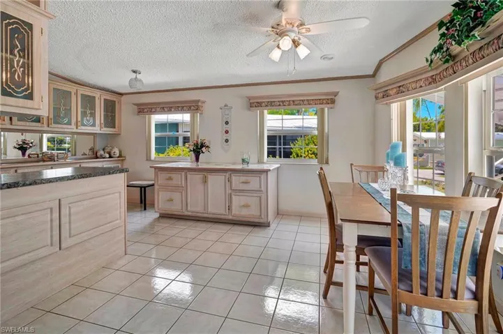Tiled dining space with a textured ceiling, ceiling fan, and crown molding