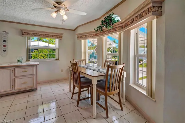 Tiled dining room featuring plenty of natural light impact glass windows, ceiling fan, a textured ceiling, and lofted ceiling