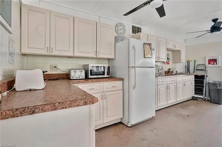 Community kitchen featuring white cabinetry, white fridge, and ceiling fan  in Everglades Kite Circle