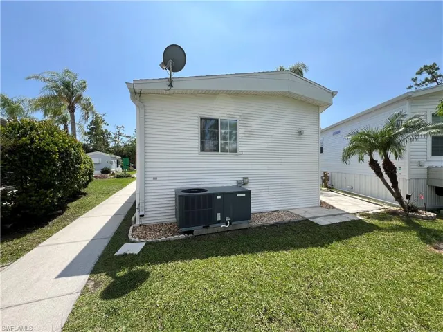 Back of property with central air condition unit and a lawn
