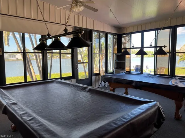 Rec room with a wealth of natural light, ceiling fan, pool table, and a water view