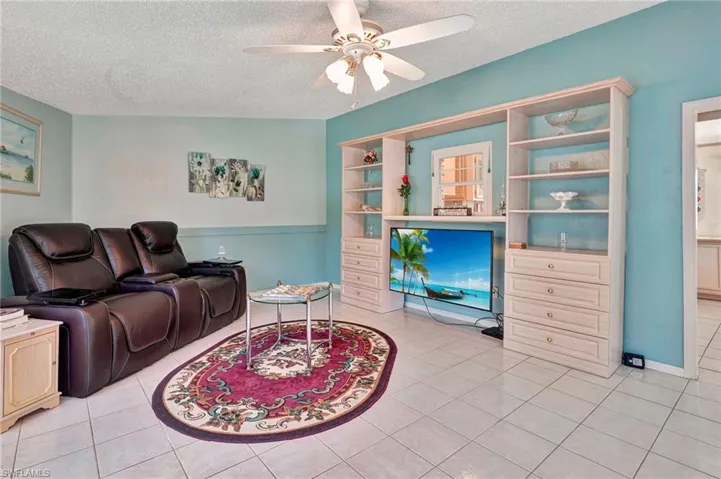 Tiled living room featuring ceiling fan and a textured ceiling