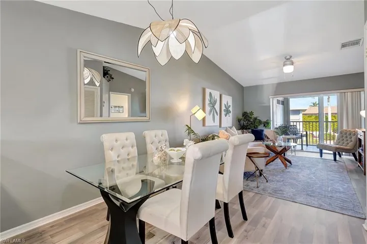 Dining room featuring light hardwood / wood-style flooring, vaulted ceiling, and ceiling fan