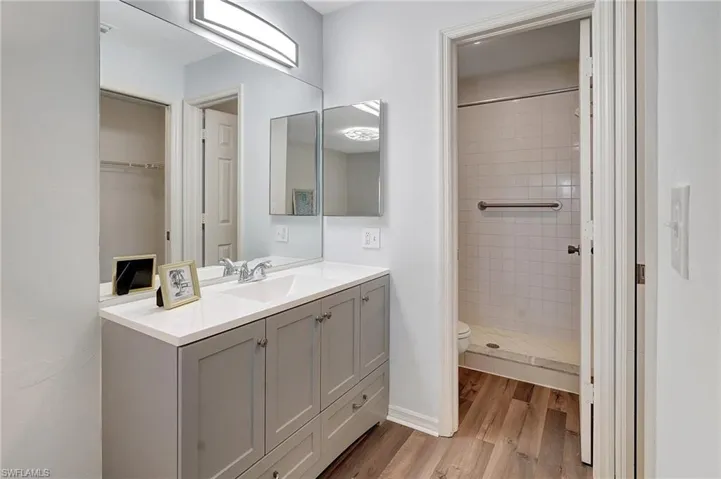 Bathroom featuring tiled shower, wood-type flooring, vanity, and toilet