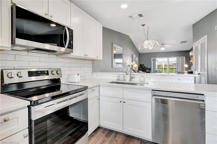 Kitchen featuring white cabinets, appliances with stainless steel finishes, kitchen peninsula, and sink
