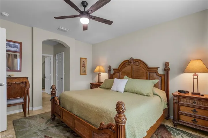 Bedroom featuring light tile patterned floors, a ceiling fan, arched walkways, and a closet