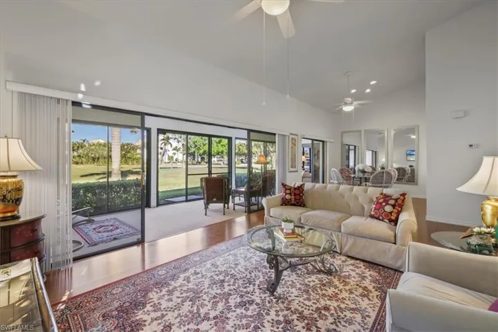 Living room featuring wood finished floors, ceiling fan, vaulted ceiling, and recessed lighting