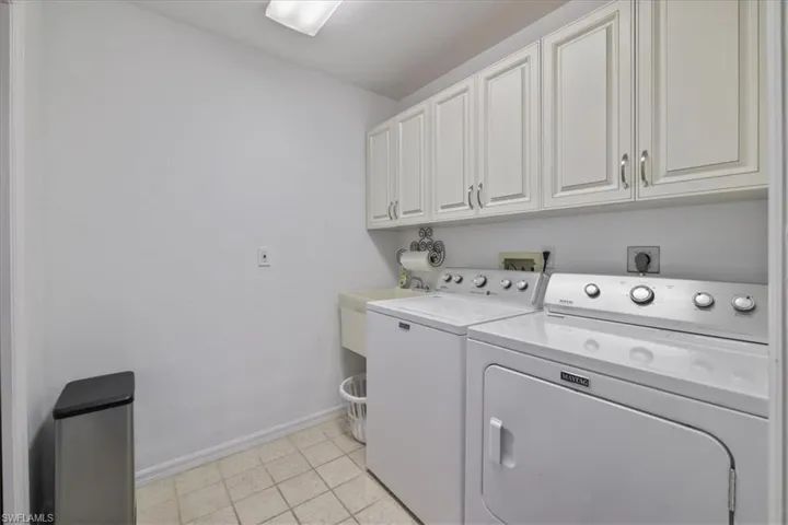Laundry area featuring cabinet space, washing machine and dryer, and light tile patterned flooring