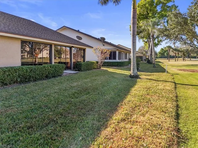 View of grassy yard with a sunroom