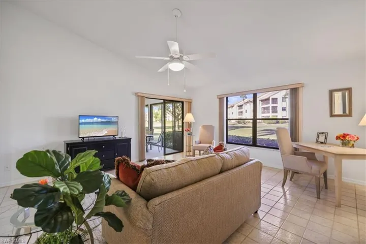 DEN with ceiling fan, light tile patterned flooring, and vaulted ceiling