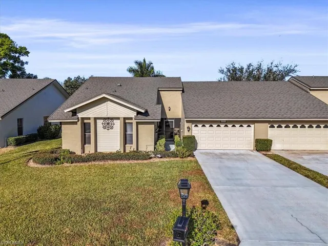 View of front of property featuring roof with shingles, driveway, a front lawn, an attached garage, and stucco siding