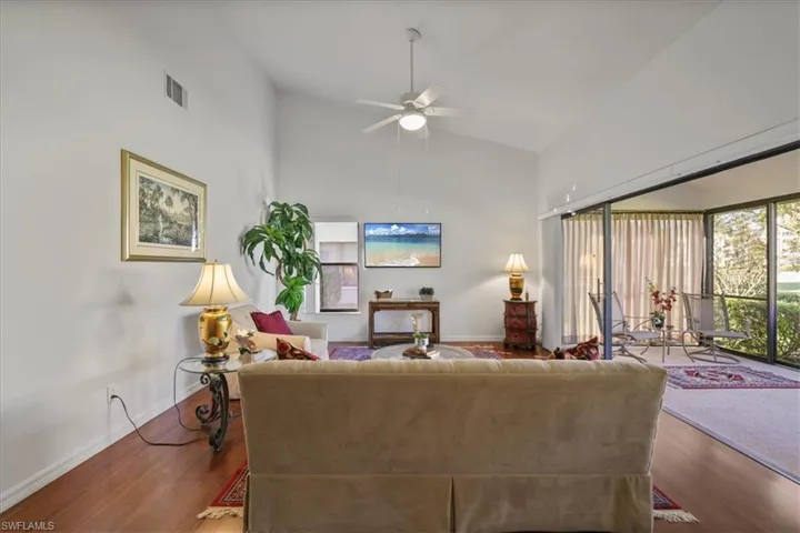 Living room featuring wood finished floors, ceiling fan, and vaulted ceiling