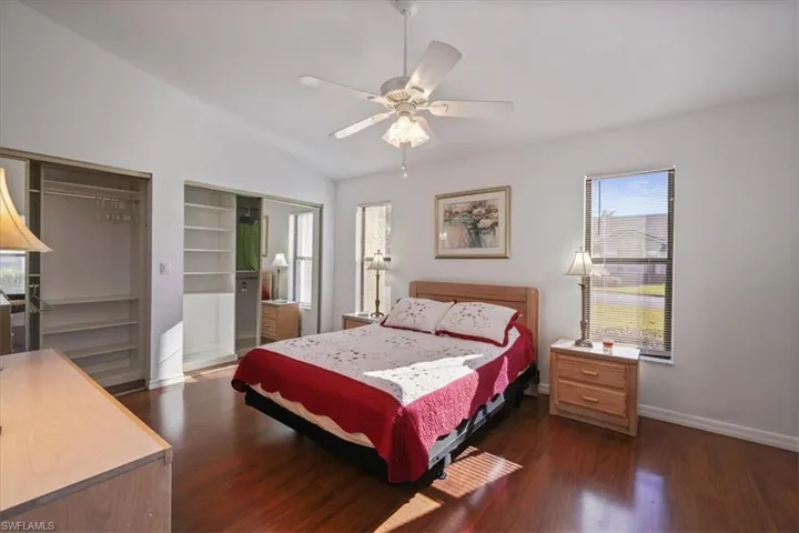 Bedroom featuring multiple closets, dark wood-type flooring, a ceiling fan, and vaulted ceiling