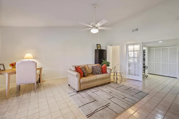 DEN featuring lofted ceiling, a ceiling fan, and light tile patterned flooring