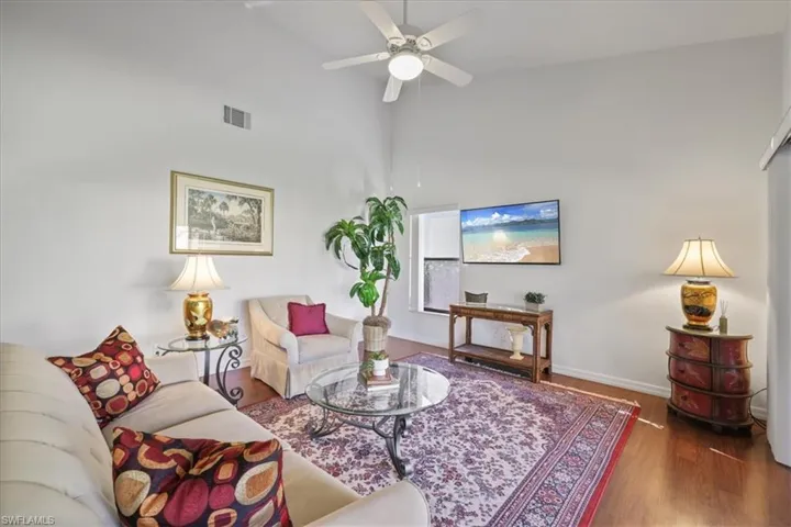 Living room featuring a high ceiling, wood finished floors, and ceiling fan