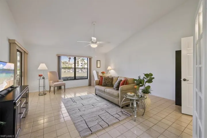 DEN with lofted ceiling, light tile patterned floors, and a ceiling fan