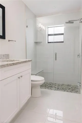 Full bath with vanity, light tile patterned floors, and a shower stall