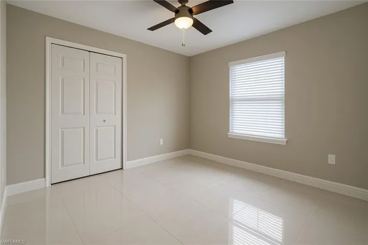 Unfurnished bedroom with light tile patterned floors, a closet, and ceiling fan