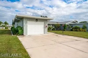 View of side of property with a lawn, concrete driveway, and an attached garage
