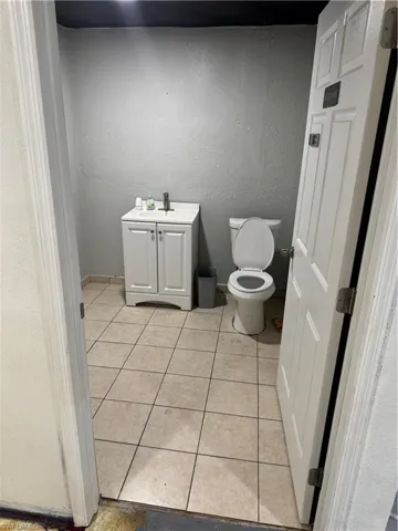 Bathroom featuring a sink, toilet, a textured wall, and tile patterned floors