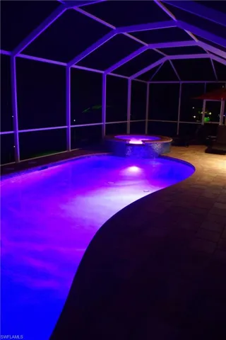 View of swimming pool featuring a patio area, an in ground hot tub, and glass enclosure
