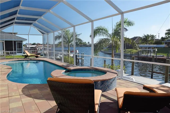 View of pool featuring a lanai, a water view, an in ground hot tub, a dock, and a patio