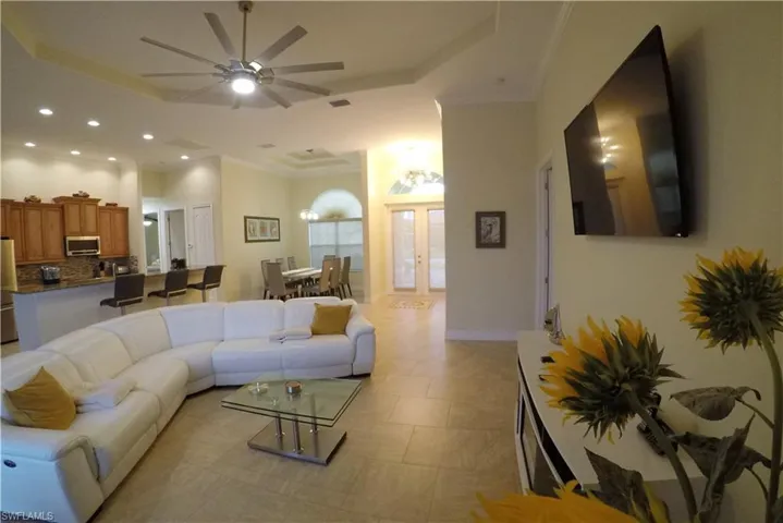Living room with a raised ceiling, ceiling fan, crown molding, and french doors