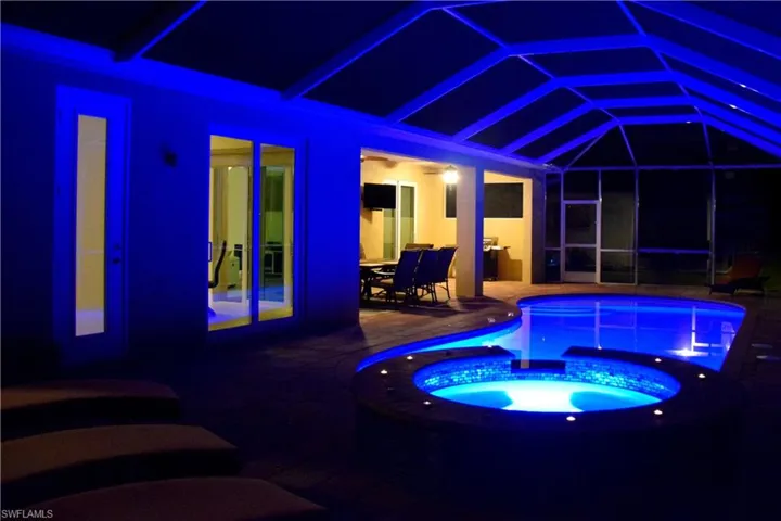 View of pool featuring glass enclosure, an in ground hot tub, and a patio