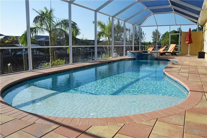 View of swimming pool featuring glass enclosure, an in ground hot tub, and a patio