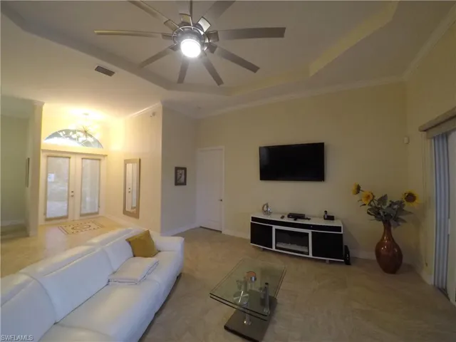 Carpeted living room featuring a tray ceiling, crown molding, french doors, and ceiling fan